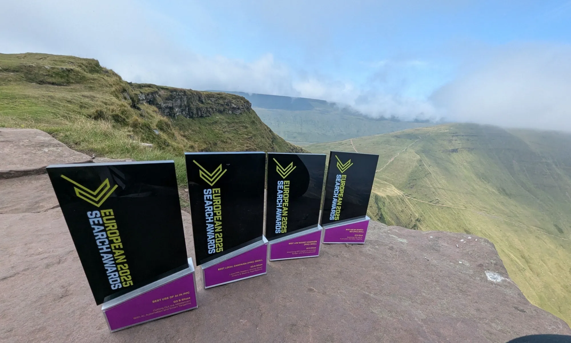 Four European Search Awards 2025 trophies on a rock ledge above a valley in Bannau Brycheiniog